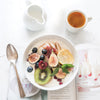 healthy breakfast with fruits and rooibos in a white bowl and a white cup