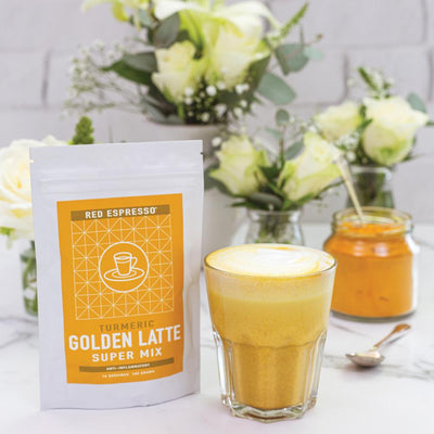 turmeric latte mix product with a beautiful flower behind